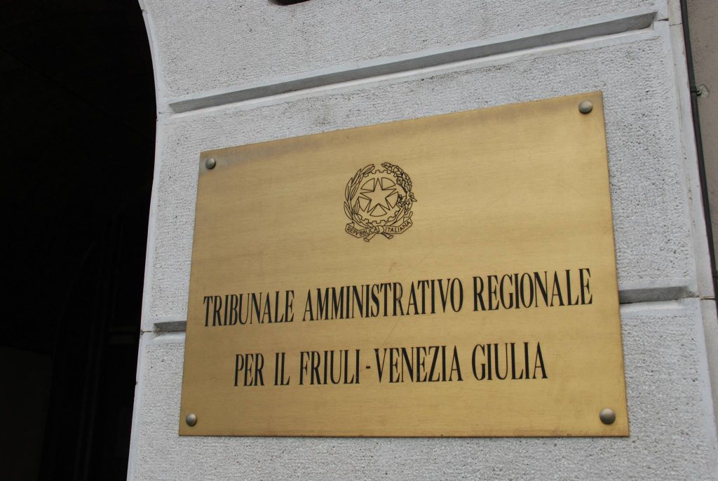 The plaque at the entrance of the Regional Administrative Court for Region Friuli Venezia Giulia. It is made of brass, the writing and the emblem of the Italian Republic are black.