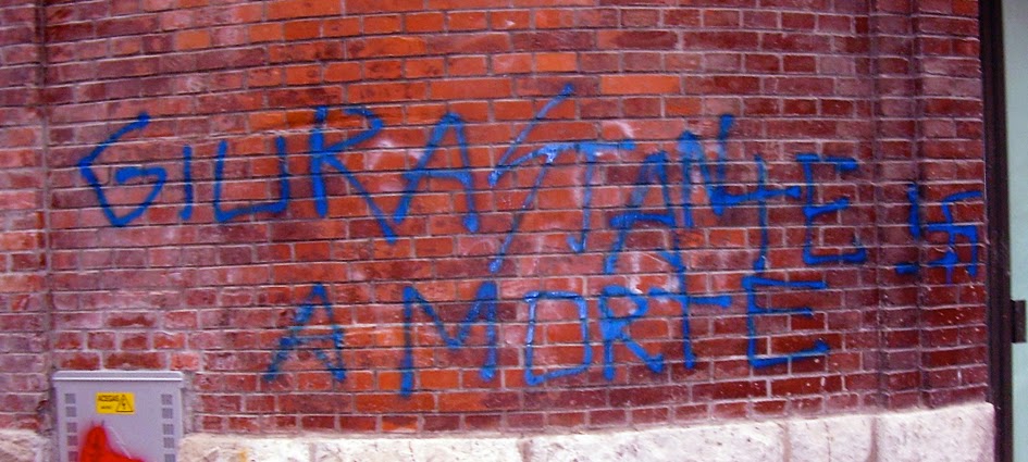 A derogatory writing "Giurastante to death" on a wall in Trieste; it does also display a Swastika and a runic S. Despite its nature and intimidating elements, it wasn't easy having it removed.